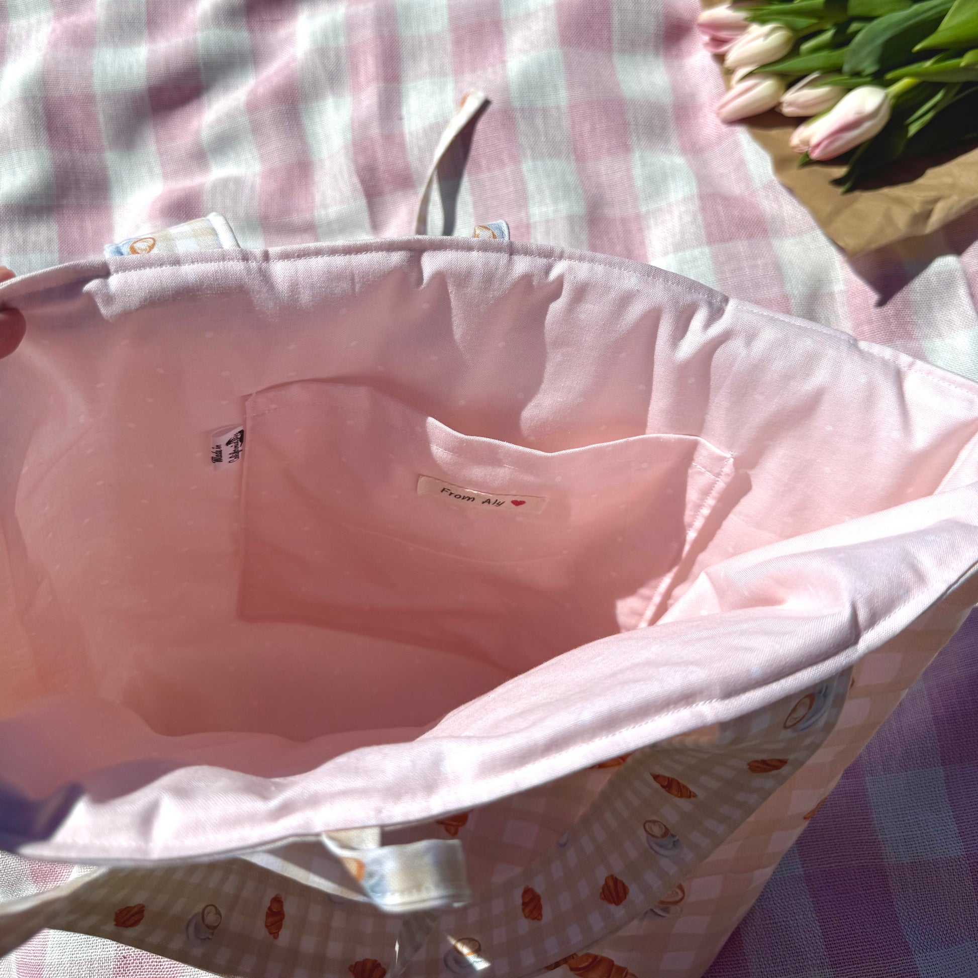 Pink tote bah liner with a brand label on a checkered fabric background