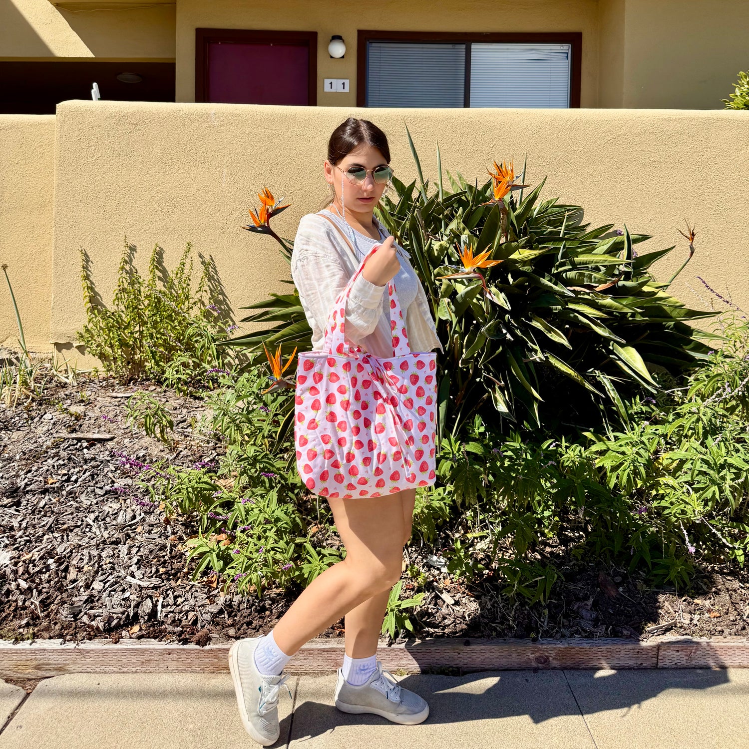 Woman holding a Strawberry Love tote bag handmade by From Aly, quilted pink and red strawberry print bag with gingham background, styled for everyday use.