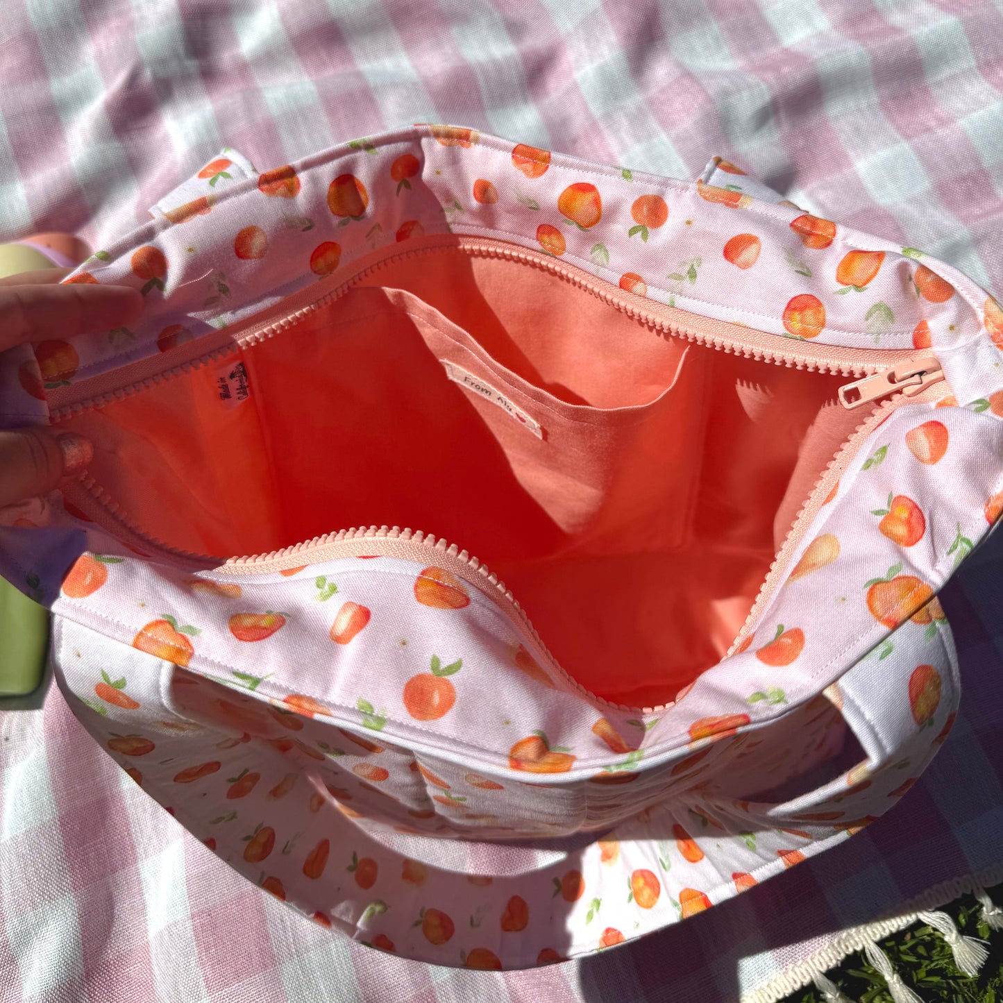 Open bag with peach colored interior on a checkered fabric background
